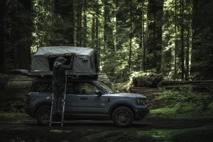 SUV camping setup with rooftop tent and outdoor utility gear